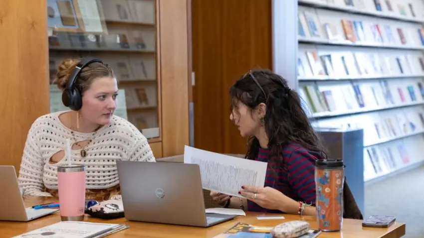 Two bentley students converse in the library