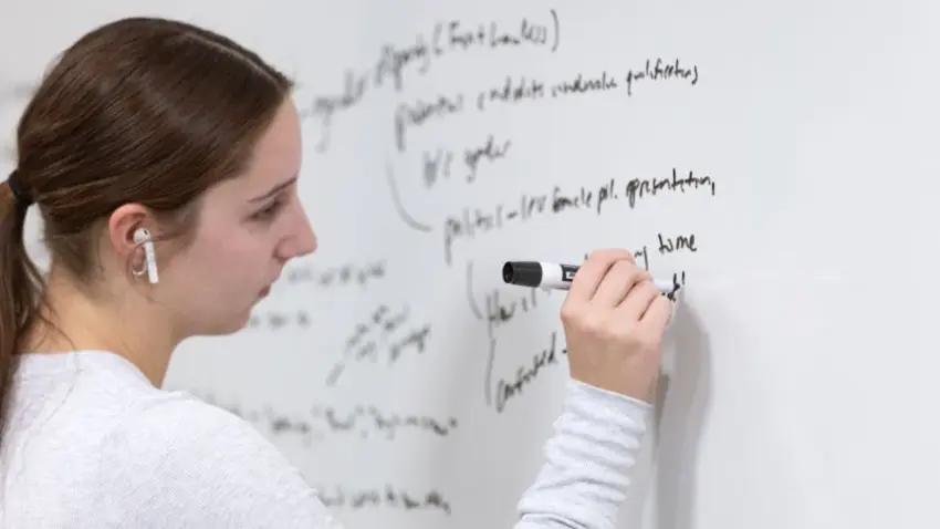 Bentley student writes on a whiteboard