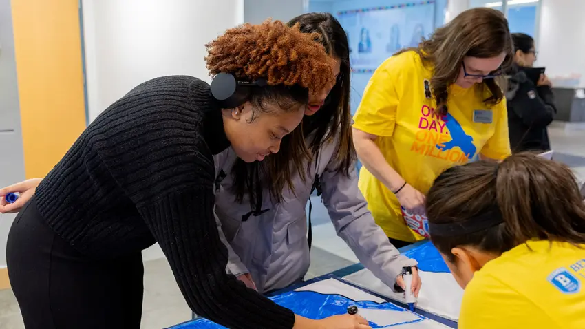woman colors a mural on giving day
