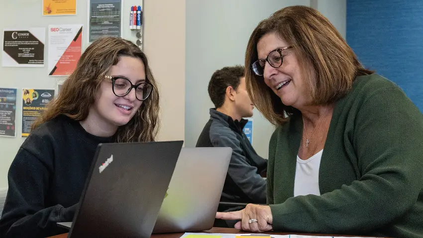 two women look at a laptop together
