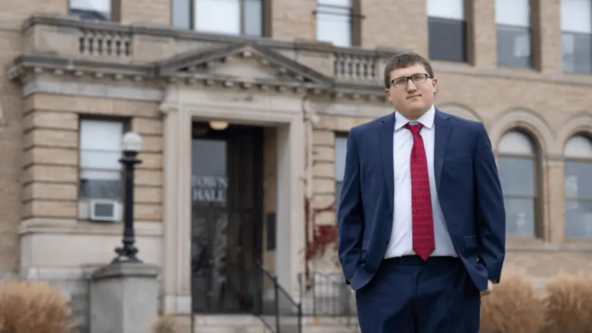 Joe Romano stands in front of Winthrop's Town Hall wearing a navy blue suit, white shirt and red tie.