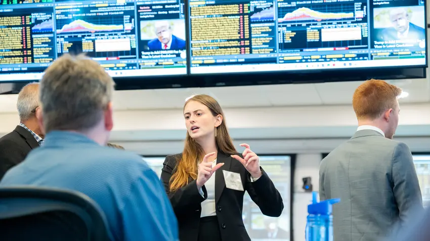 Female graduate student dressed in professional attire lectures adult learners in a high-tech business lab 