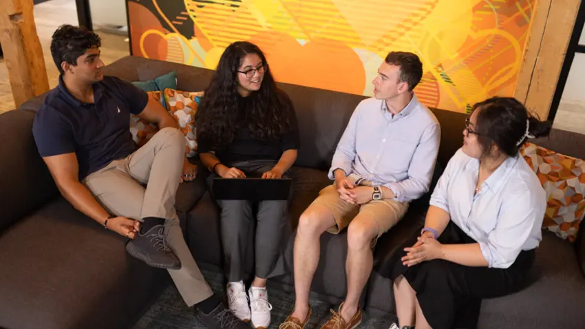 four students sit in office space talking 