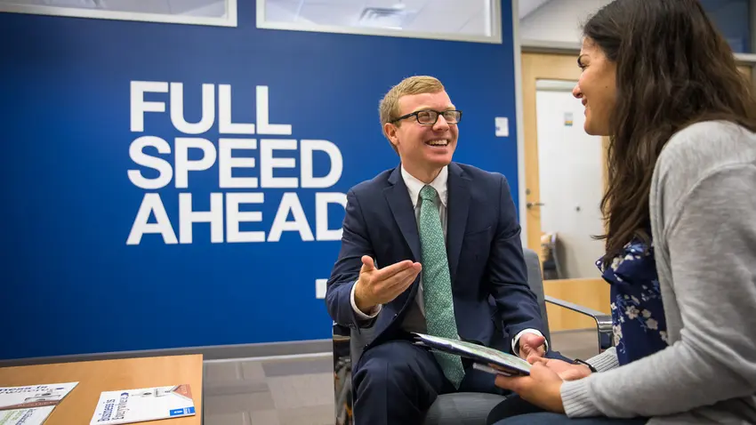 Photo of two students, one in a suit, talking