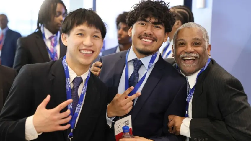 Three attendees come together in friendly embrace to pose at the Bentley Mankind Movement annual networking conference