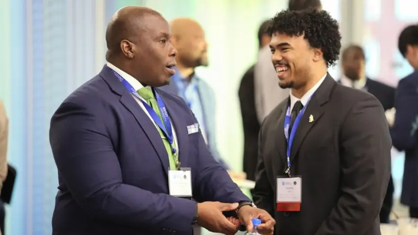 Two attendees shake hands and converse at the Bentley Mankind Movement networking conference