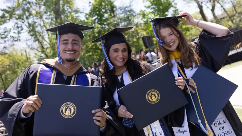 Friends from the Bentley Class of 2026 poses with their diplomas at Commencement ceremonies