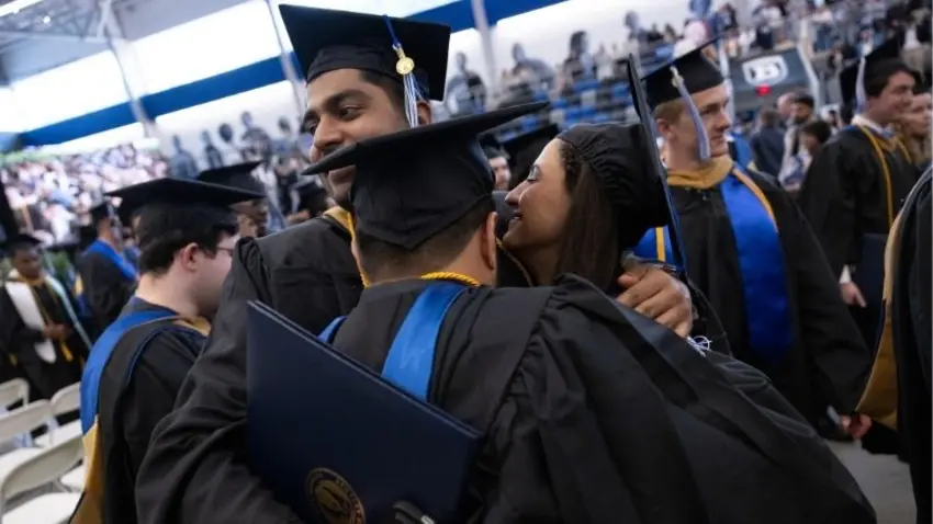 Class of 2026 graduates embrace during the Bentley McCallum Graduate School of Business 51st commencement ceremony. 