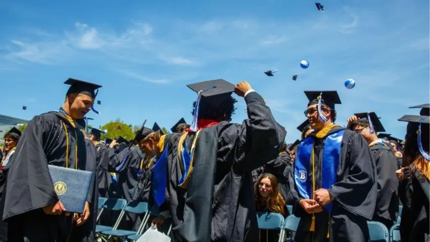 Bentley Class of 2026 graduates look up at caps in the air as they celebrate the end of commencement ceremonies