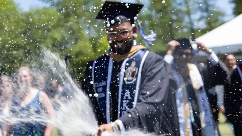 Bentley Class of 2026 graduate pops a bottle of champagne after the commencement ceremony ends