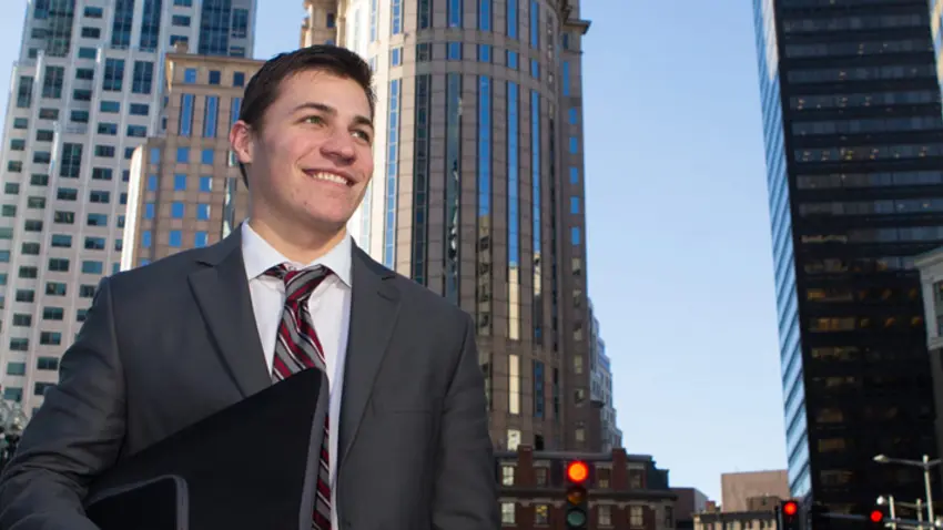 Man in suit standing in front of large buildings in the city
