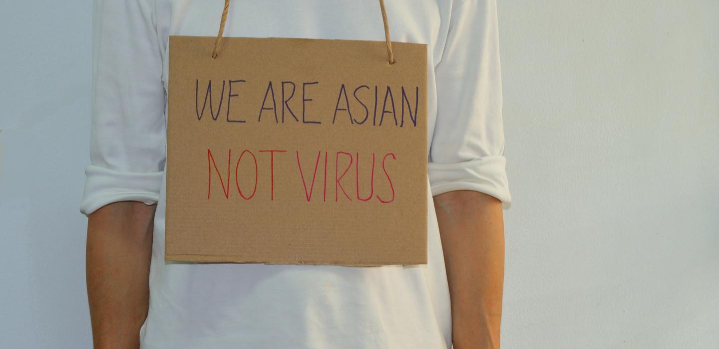 Man wearing sign that reads "We are Asian, not virus."