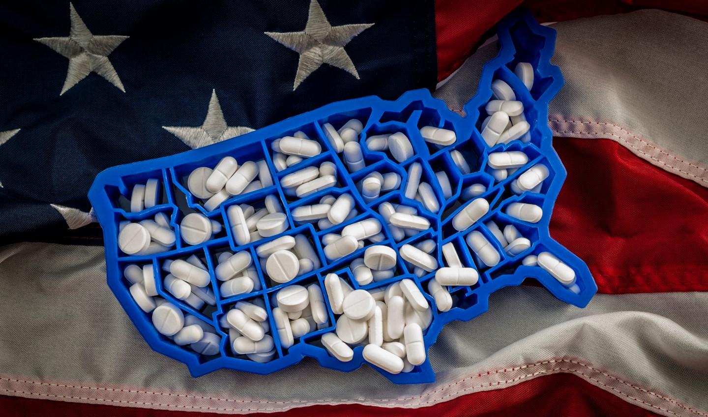 Pill box in the shape of the United States on top of an American flag