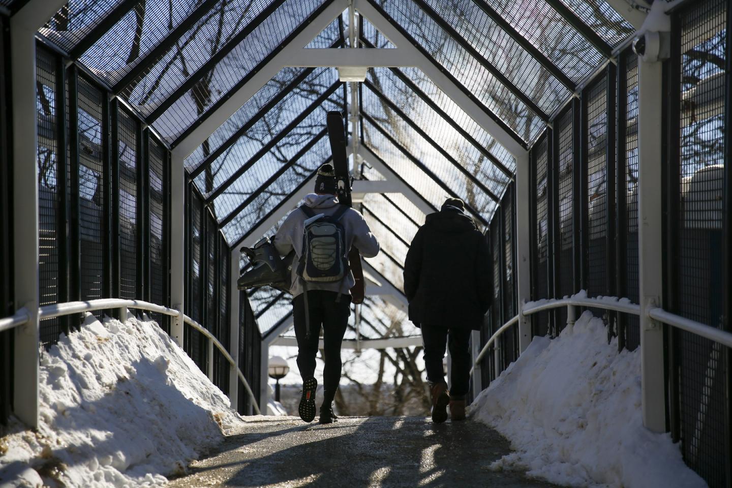 Students walk over the footbridge in the snow