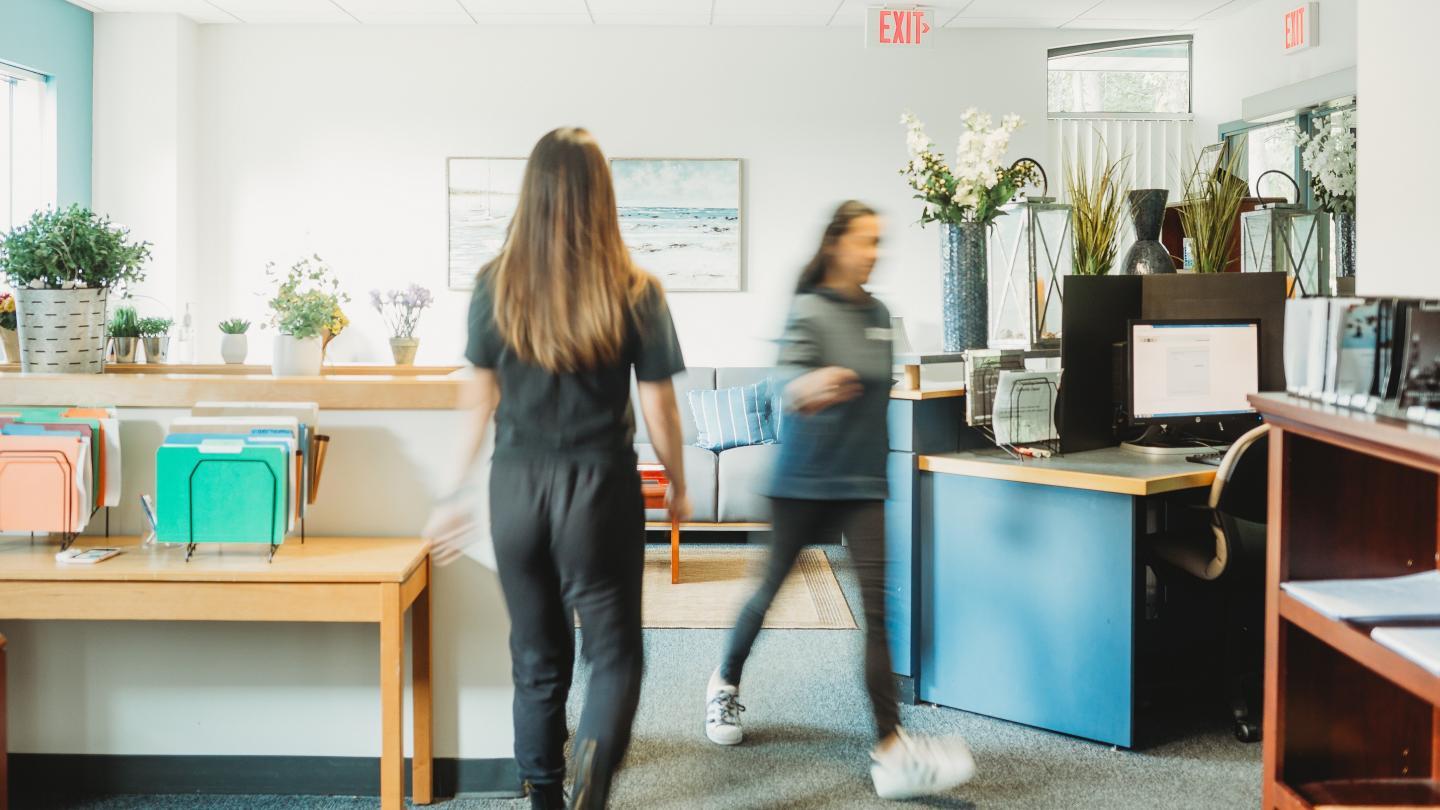 Two healthcare professionals walking in a light colored health office