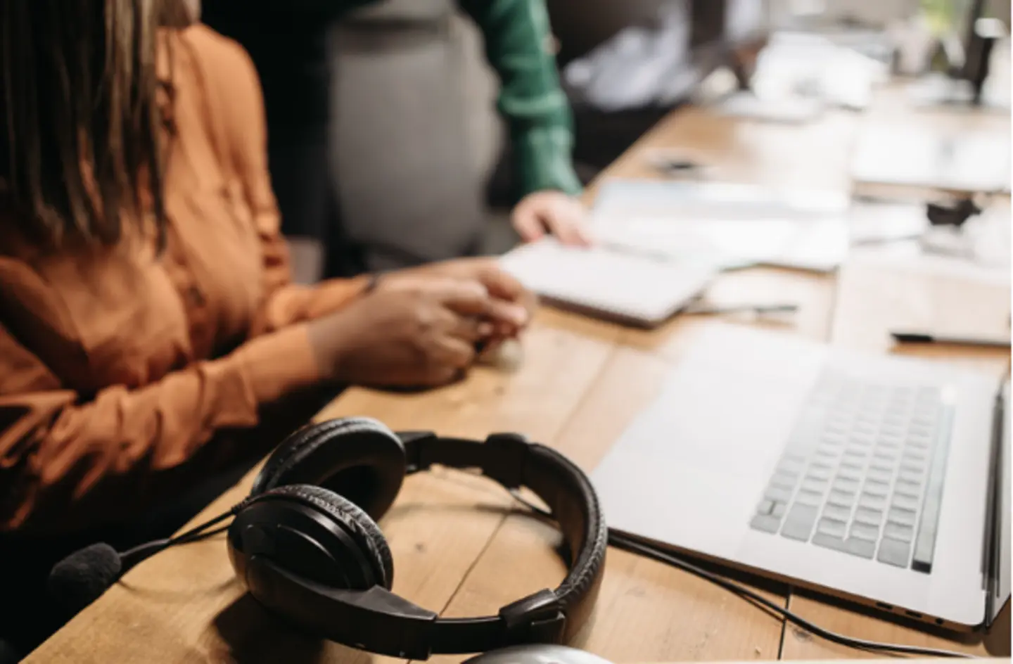 employee working at desk with laptop and headphones nearby