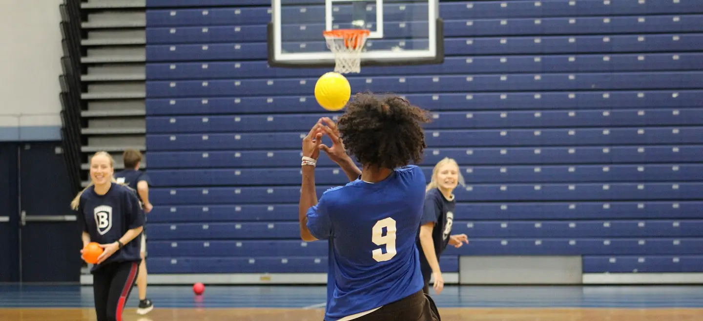 Three Bentley students play on a basketball court in the Dana Athletic Center.