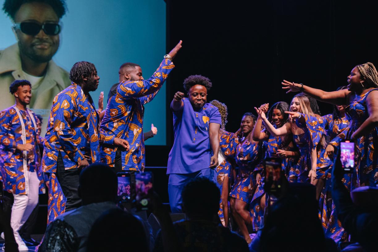 Crowd wearing blue-tone African attire dance on stage