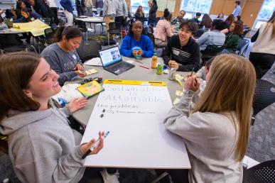 Students brainstorming around a table at the Junior Achievement Be Entrepreneurial Challenge held at Bentley University