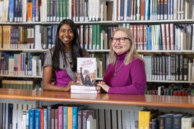 Bentley alumna Edith Joachimpillai and professor Mary Marcel pose with a copy of their new book, "This Era of Black Activism," in the Bentley Library.