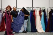 Bentley students showcase prom dresses in various colors with dress rack in background